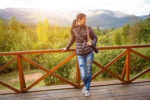 A woman with a camera stands against the background of nature and mountains photo