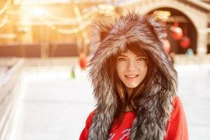 mujer joven feliz en un sombrero de lobo en invierno en la pista de hielo foto