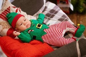 Christmas concept little boy cheerful elf looking up lies on multi-colored photo