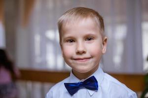 Portrait of a boy in white shirt and black bow tie, smiling cheerful schoolboy photo