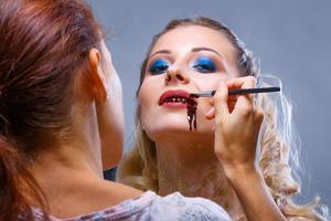 make up artist makes and applies makeup to the model photo