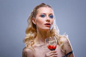 bright make-up on the face of a beautiful woman holding a glass of wine in her hand photo