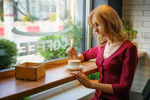 beautiful woman sitting by the window in a cafe drinking coffee. photo