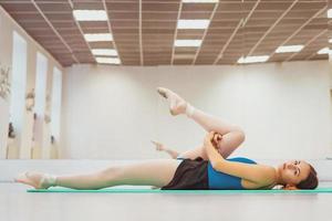 cute gymnast engaged in training in the hall, stretching on the Mat photo