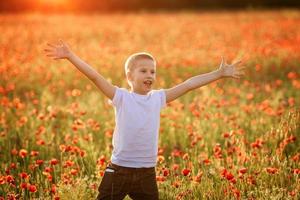 retrato de un niño feliz de 10 años en un campo de amapolas foto