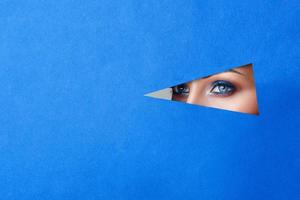 beautiful young woman in a hole in blue paper, beautiful bright make-up. photo