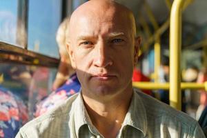Travel safely by public transport. A young bald man looks through bus window. photo