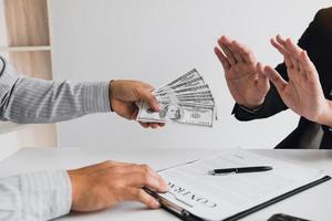 Business person refusing bribe given money by partner with anti bribery corruption concept. photo