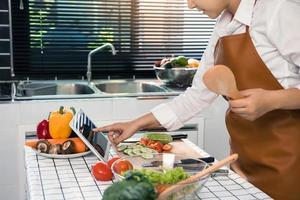 Asian woman is searching for a recipe website for cooking on a tablet in the kitchen. photo