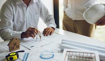 Two architect working at construction site and compass drawing pointing on blueprint with partnership. photo