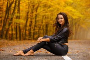 beautiful young woman sitting in autumn Park on road in black photo