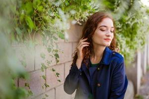 beautiful young woman with red hair and freckles on background of wall photo