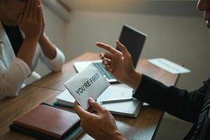 Male manager is talking or explaining about having to dismiss the employee while being handed out a resignation envelope to the employee. photo