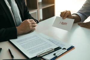 Female employee is submitting an envelope requesting a resignation from the company to the manager. photo