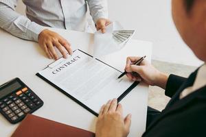 los empresarios están firmando un contrato sobre negocios bajo fraude mientras sus colegas dan dinero en un sobre. foto