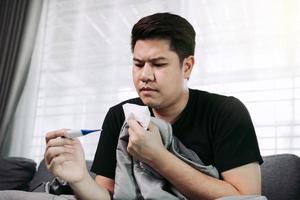Asian people feel stressed because having cough and cold and using a thermometer to check if he has fever or illness at his home. photo