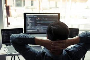 Asian programmers man are relaxing and looking at the code on the computer screen in the office. photo