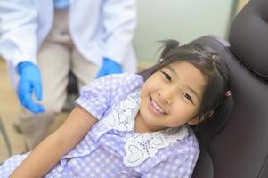 una niña linda con los dientes examinados por un dentista en una clínica dental, un chequeo dental y un concepto de dientes sanos foto