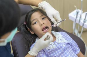 una niña linda con los dientes examinados por un dentista en una clínica dental, un chequeo dental y un concepto de dientes sanos foto