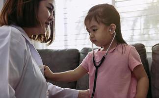 Cute little girl using stethoscope to listen to doctor heartbeat. photo