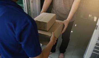 cerca de las manos el personal de carga está entregando cajas de cartón con paquetes dentro de la mano del destinatario. foto