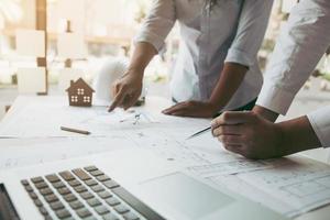 Two architect working at construction site and compass drawing pointing on blueprint with partnership. photo