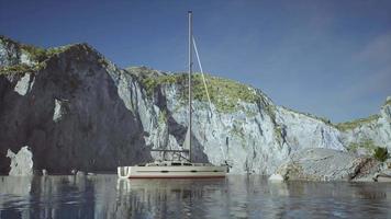 White yacht anchored in a bay with rocky cliffs video