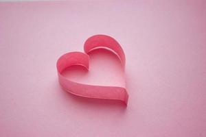 Beautiful pink paper heart on pink background with copy space. Quilling, origami, handmade. Minimalism photo