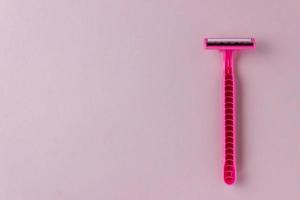 Pink one-time female razor on a pink background with copy space. Bright colors, minimalism. Smooth legs, daily self-care photo