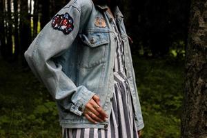 chica con chaqueta vaquera y vestido a rayas en el bosque foto