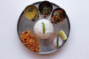 thali indio es un plato servido en un plato con varios platos, arroz, pescado, alu baja, dal foto