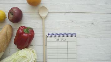 Full paper bag of food products with blank little notebook on wooden table, top view photo