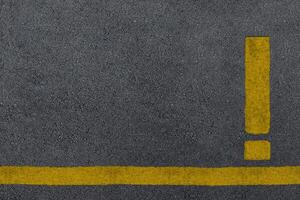 Yellow exclamation mark sign painted on a asphalt road surface photo