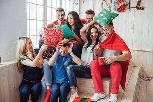 Crazy young best friends fighting pillows at home. Mixed race group of people. Concept  entertainment and lifestyle photo