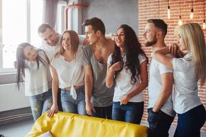 Group portrait of multi-ethnic boys and girls with colorful fashionable clothes holding friend posing on a brick wall, Urban style people having fun, Concepts about youth togetherness lifestyle photo