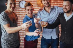 viejos amigos alegres se comunican entre sí con vasos de whisky en el pub. concepto de entretenimiento y estilo de vida foto