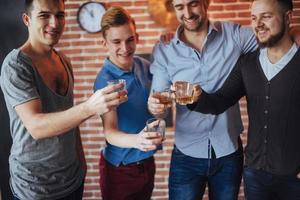 viejos amigos alegres se comunican entre sí con vasos de whisky en el pub. concepto de entretenimiento y estilo de vida foto