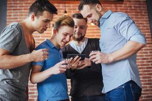 Cheerful old friends communicate with each other and phone watch,  glasses of whiskey in pub. Concept  entertainment  lifestyle. Wifi connected people in bar table meeting photo