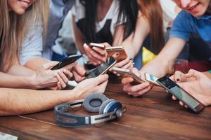 Top view hands circle using phone in cafe - Multiracial friends mobile addicted interior scene from above - Wifi connected people in bar table meeting - Concept of teamwork photo