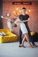 Young couple dancing latin music. Bachata, merengue, salsa. Two elegance pose on cafe with brick walls photo