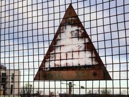 Warning sign rusty back with stuck snow on wire fence photo