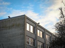 antiguo edificio de paredes de ladrillo blanco en la esquina con ventanas cuadradas en el fondo del cielo foto