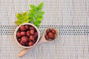 Gooseberry in syrup put in wood bowl and spoon on bamboo wicker, Mayom chueam photo