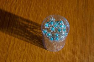 Group of white metal hairpins with beaded flowers in can on the table photo