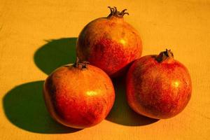 Three ripe pomegranates on the wooden table photo