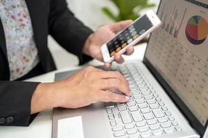 Asian accountant working and analyzing financial reports project accounting with chart graph and calculator in modern office, finance and business concept. photo