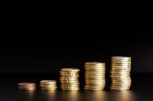 Rising Coin stacks on black background. Growth, income, savings concept. Copy space photo