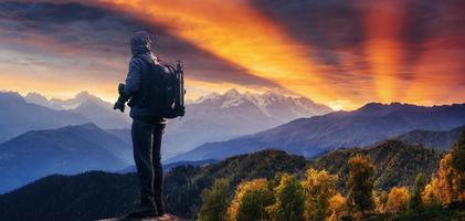 Professional photographer takes photos with big camera on peak of rock