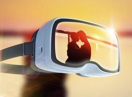 auriculares de realidad virtual, doble exposición, pareja romántica en la playa con un colorido fondo de puesta de sol foto