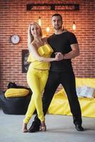 Young couple dancing latin music Bachata, merengue, salsa. Two elegance pose on cafe with brick walls photo